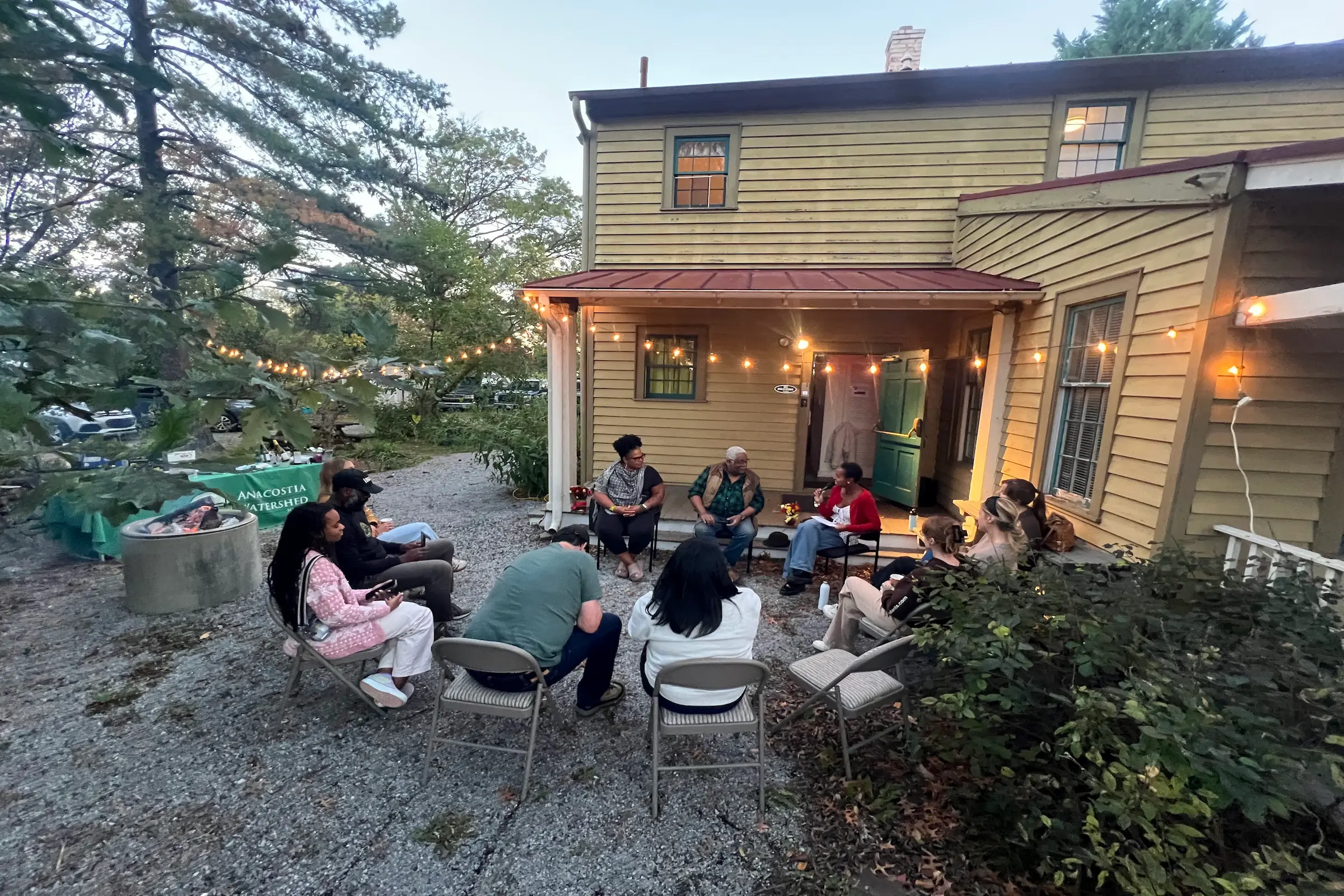 image shows people sitting outside in a discussion circle